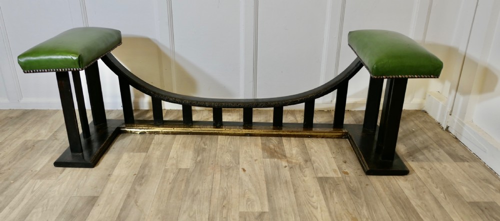 An Arts and Crafts dark oak club fender featuring two green leather upholstered seats with brass studding above vertical timber slats. View VI