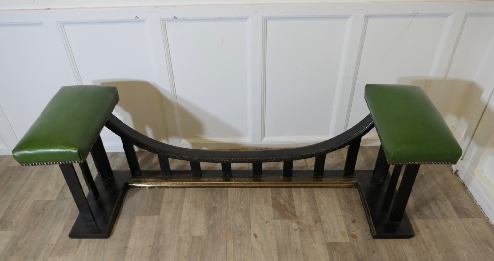 An Arts and Crafts dark oak club fender featuring two green leather upholstered seats with brass studding above vertical timber slats. View VII