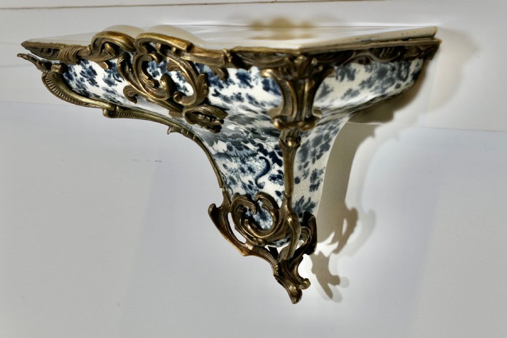 A Rococo revival wall bracket featuring blue and white floral glazed ceramic enclosed in ornamental gilt bronze foliage scrollwork. View IV