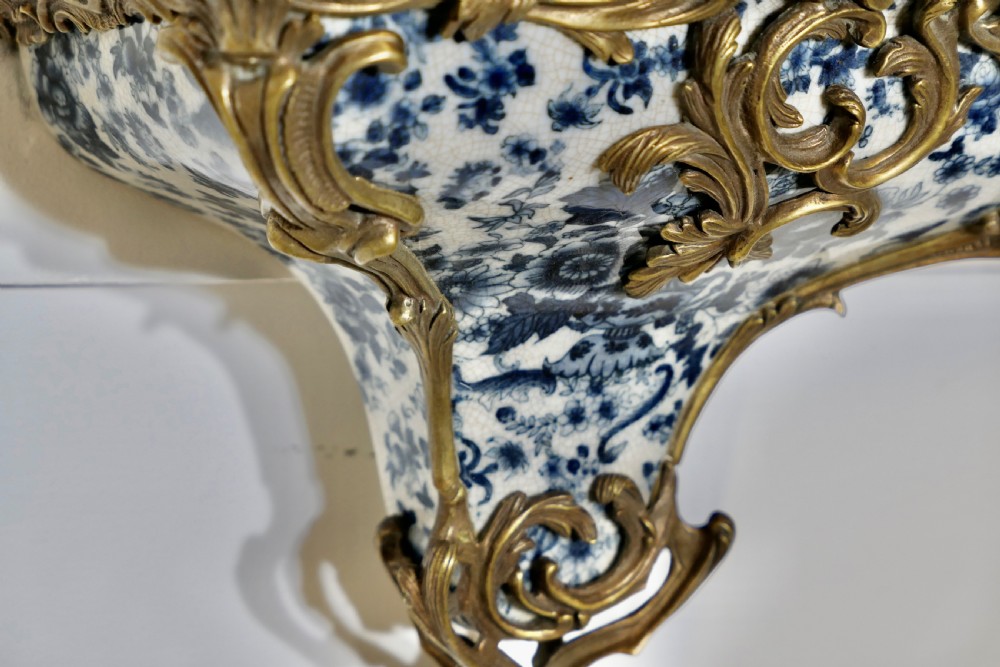A Rococo revival wall bracket featuring blue and white floral glazed ceramic enclosed in ornamental gilt bronze foliage scrollwork. View VI