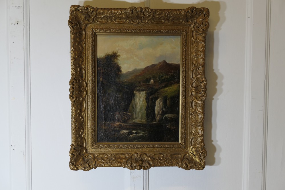 An antique Victorian oil painting depicting a cascading waterfall in a mountainous landscape, framed within an ornate gilded frame. View III