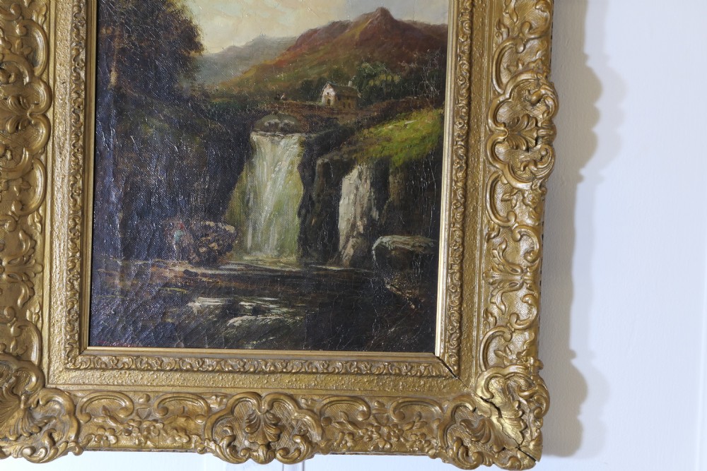 An antique Victorian oil painting depicting a cascading waterfall in a mountainous landscape, framed within an ornate gilded frame. View IV