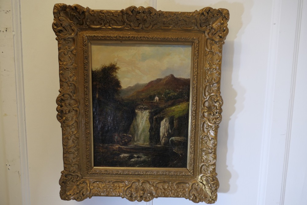 An antique Victorian oil painting depicting a cascading waterfall in a mountainous landscape, framed within an ornate gilded frame. View VIII