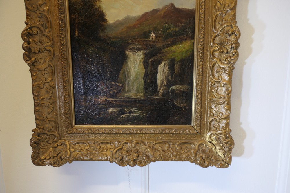 An antique Victorian oil painting depicting a cascading waterfall in a mountainous landscape, framed within an ornate gilded frame. View IX