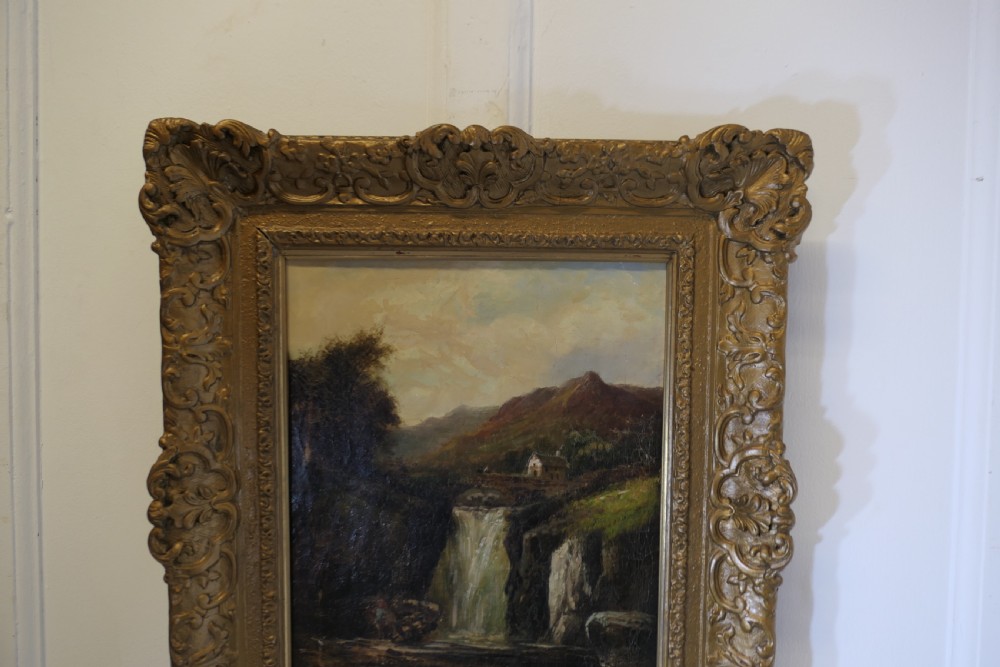 An antique Victorian oil painting depicting a cascading waterfall in a mountainous landscape, framed within an ornate gilded frame. View X