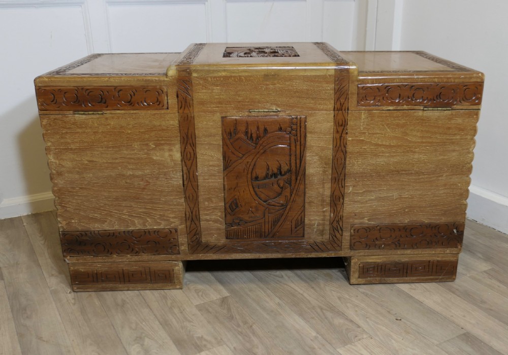 An Art Deco limed oak storage chest featuring horizontal ribbed side moulding, relief carved dragon panels, and a central brass lock plate. View III
