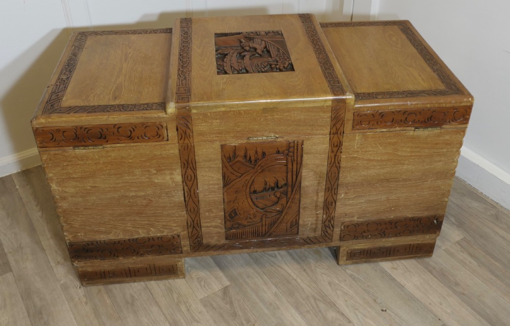 An Art Deco limed oak storage chest featuring horizontal ribbed side moulding, relief carved dragon panels, and a central brass lock plate. View IV