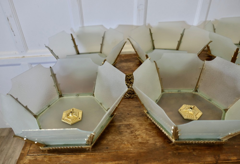 A set of six Art Deco Odeon-style pendant light shades featuring angular frosted glass panels set within brass frames. View VIII