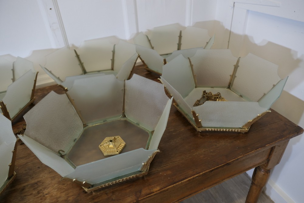 A set of six Art Deco Odeon-style pendant light shades featuring angular frosted glass panels set within brass frames. View X