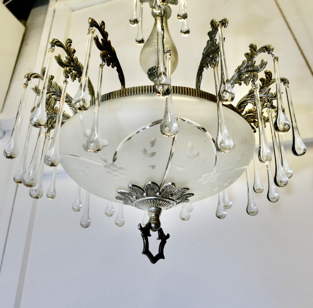 A brass and frosted glass bowl chandelier featuring scrollwork detailing and hanging teardrop crystal drops. View IV