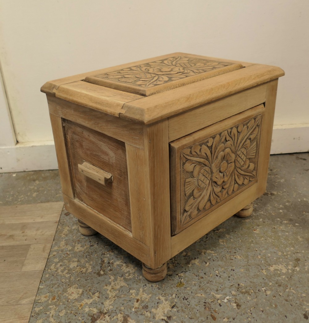 A rectangular bleached oak Arts and Crafts coal purdonium featuring a detailed floral carving on the front panel and low turned feet. View III