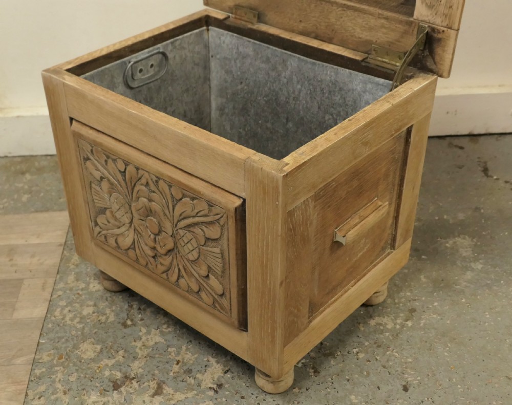 A rectangular bleached oak Arts and Crafts coal purdonium featuring a detailed floral carving on the front panel and low turned feet. View IV