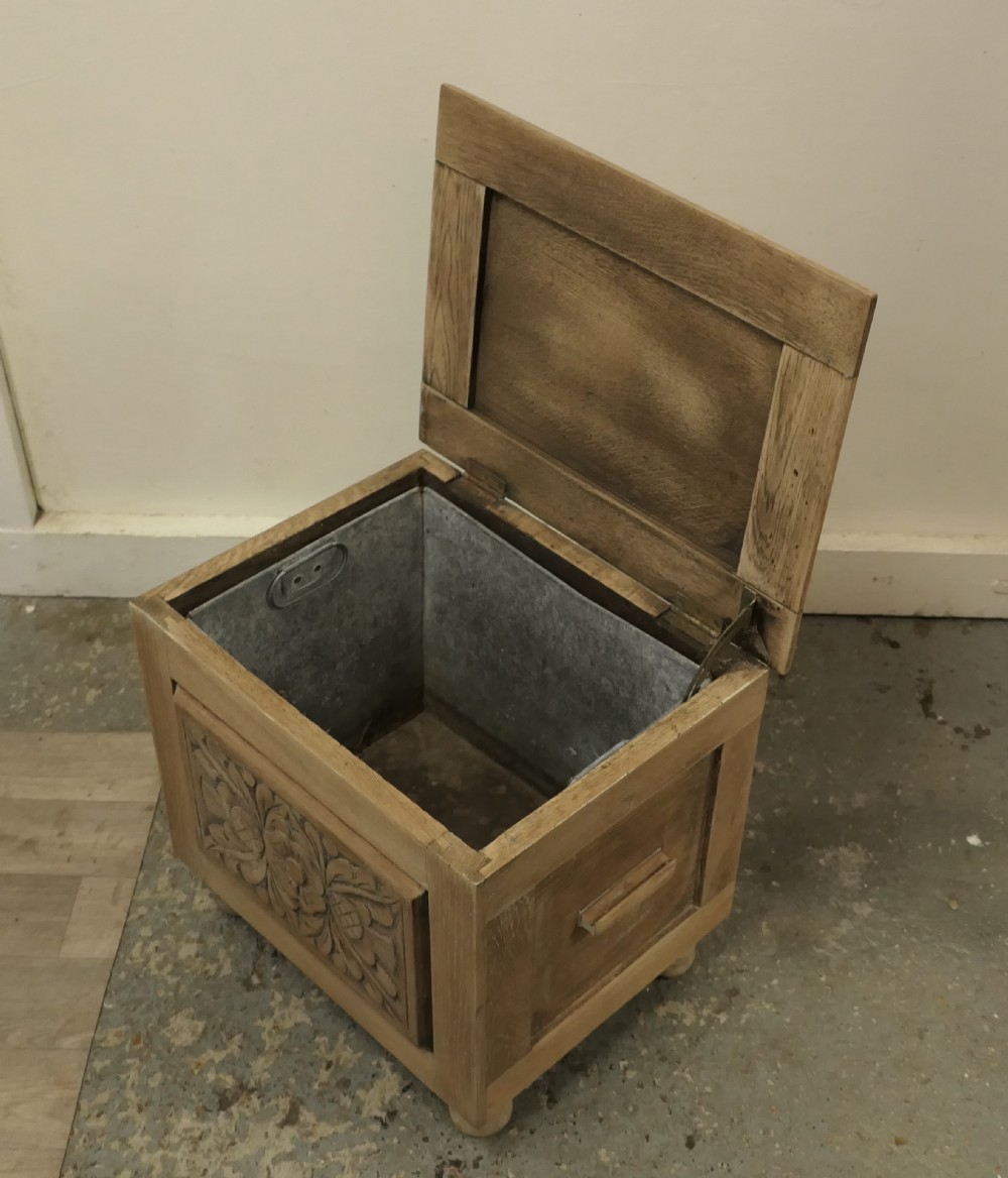 A rectangular bleached oak Arts and Crafts coal purdonium featuring a detailed floral carving on the front panel and low turned feet. View V