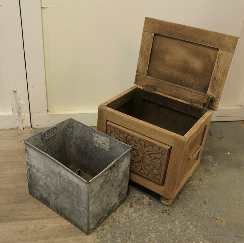 A rectangular bleached oak Arts and Crafts coal purdonium featuring a detailed floral carving on the front panel and low turned feet. View VI