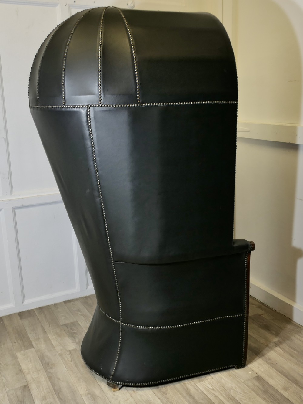 A 19th-century tall hooded hall porter chair upholstered in dark leather with stud trim and a wood base. View IX