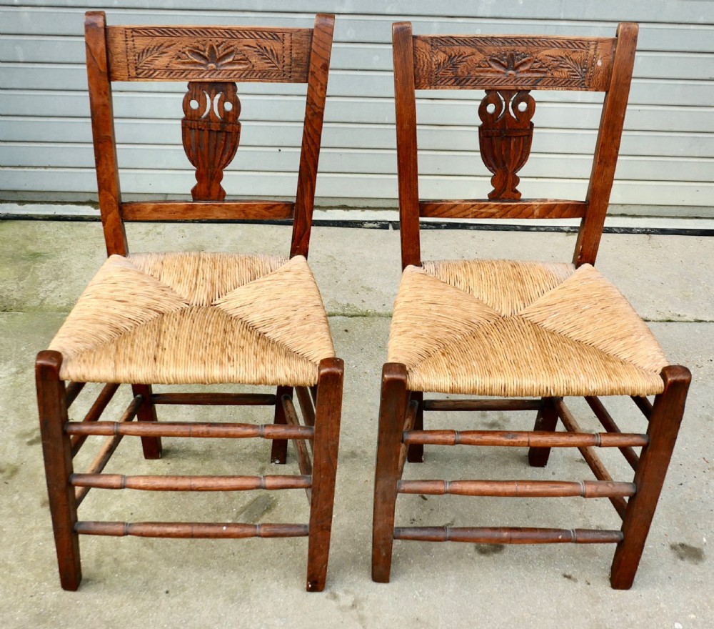 A pair of early 19th-century elm side chairs featuring carved back crests, urn-shaped splats, and woven rush seats. View III