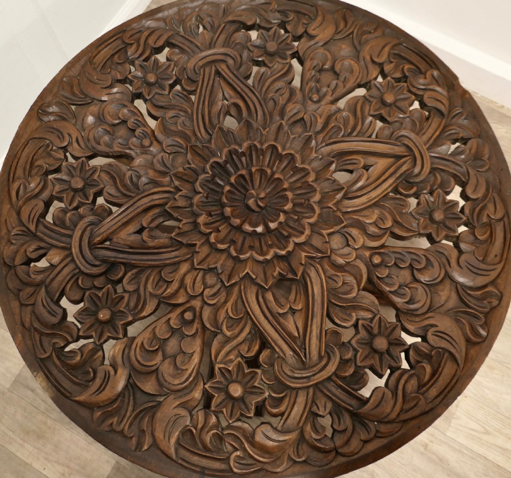 A low circular coffee table made of dark walnut wood featuring a glass top surface, a heavy turned pedestal baluster, and a four-star carved base. View III