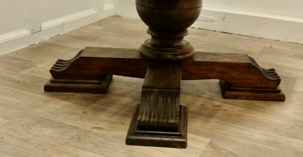 A low circular coffee table made of dark walnut wood featuring a glass top surface, a heavy turned pedestal baluster, and a four-star carved base. View VII