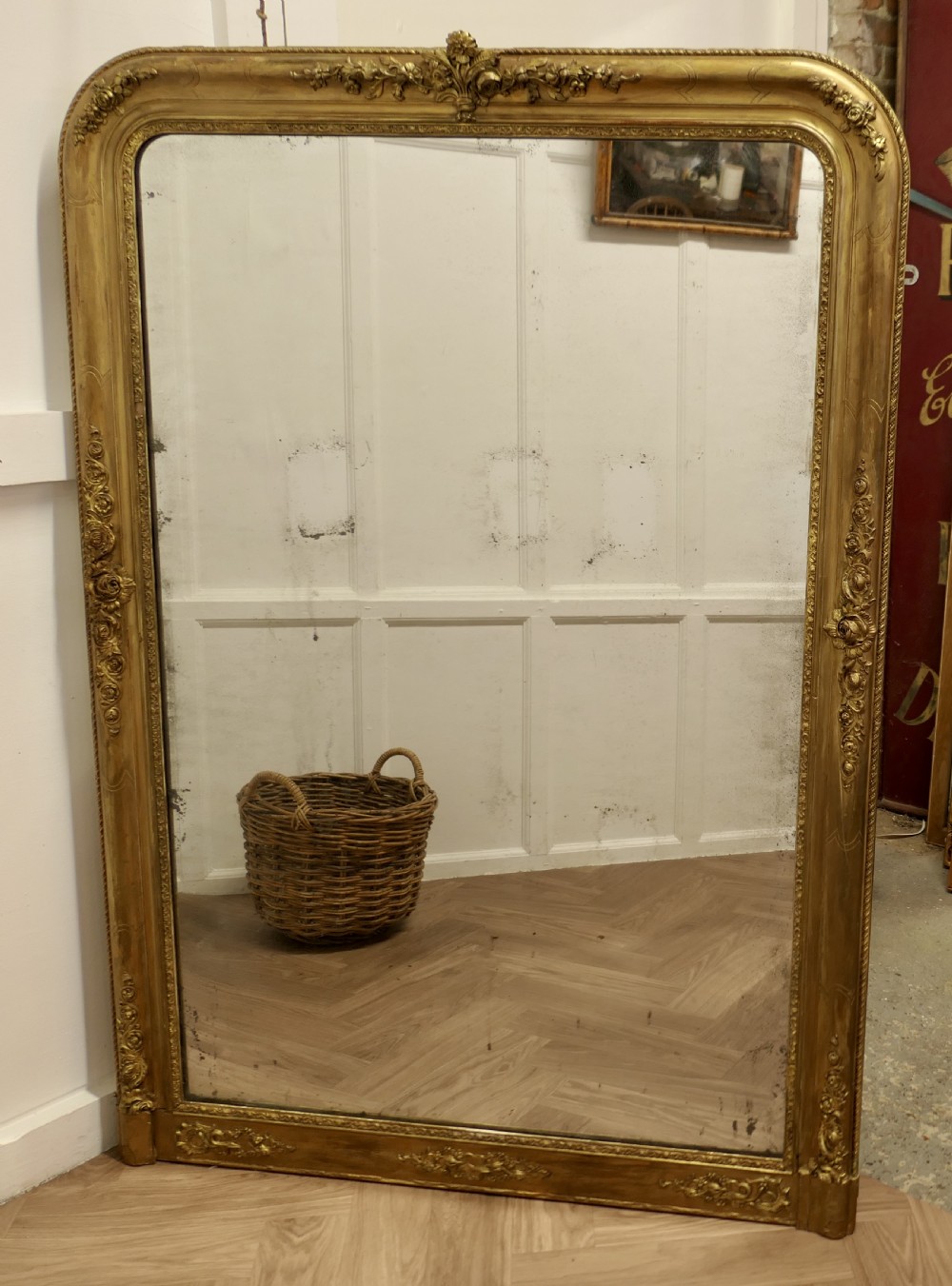 A large 19th-century French Louis Philippe style mirror with a gilded frame featuring rounded top corners and carved floral decoration. View IV