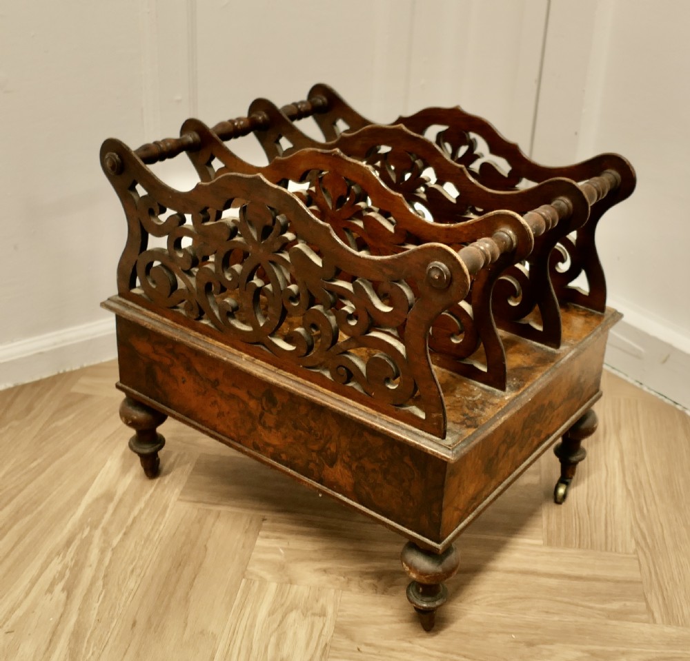 A Victorian walnut Canterbury featuring carved fretwork dividers, a single lower drawer with wooden knobs, turned legs, and brass castors. View VIII