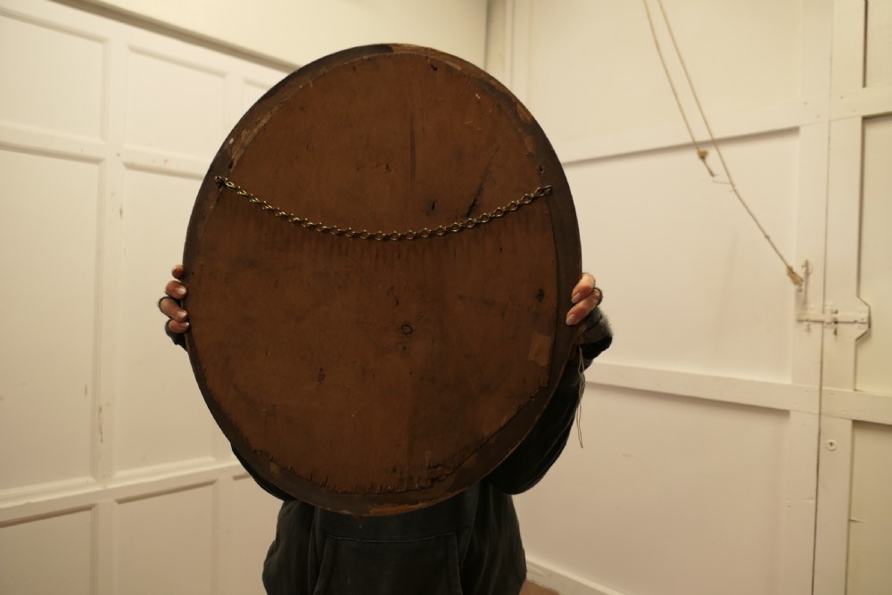 A nineteenth-century French oval wall mirror with an ornate gold leaf frame decorated with leaf motifs and a crest at the top. View VIII