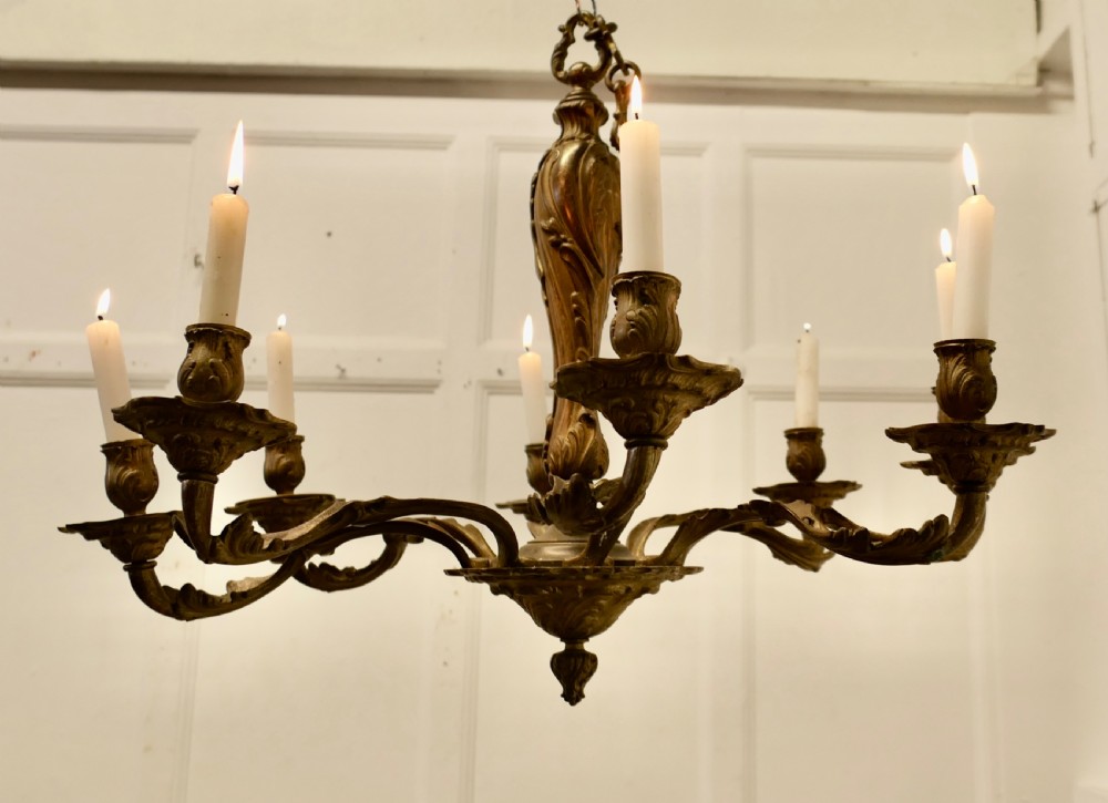 An eight-arm French Rococo style chandelier crafted from cast gilded brass with scrolling foliate arms and candle holders. View III