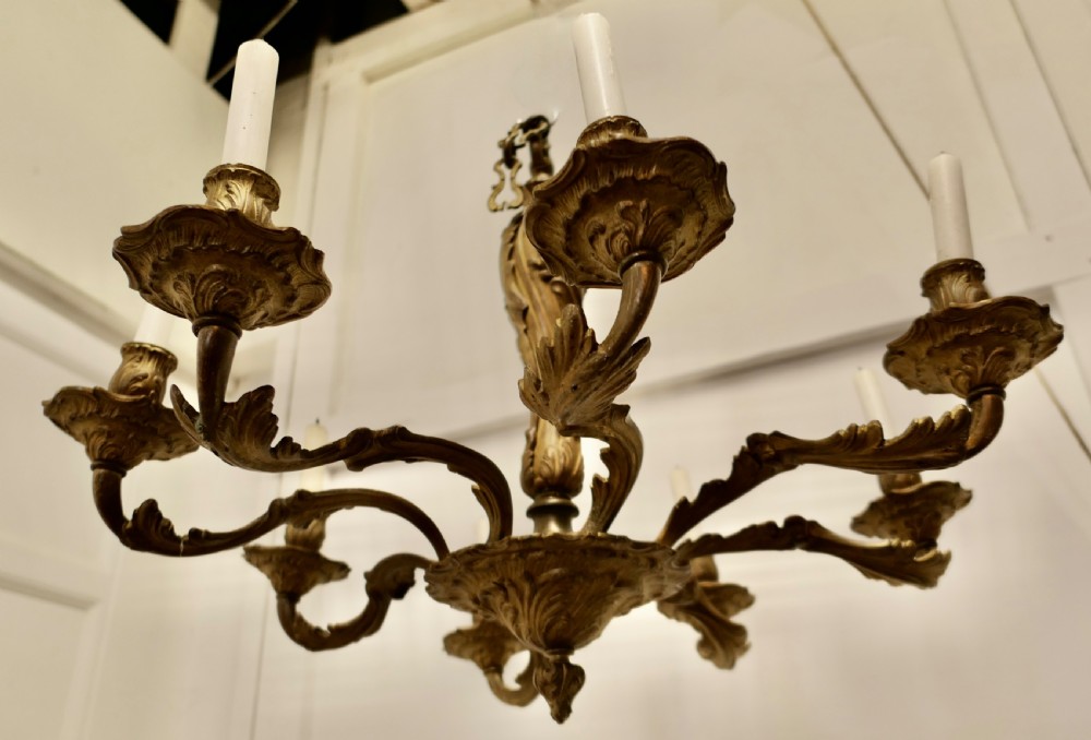 An eight-arm French Rococo style chandelier crafted from cast gilded brass with scrolling foliate arms and candle holders. View V
