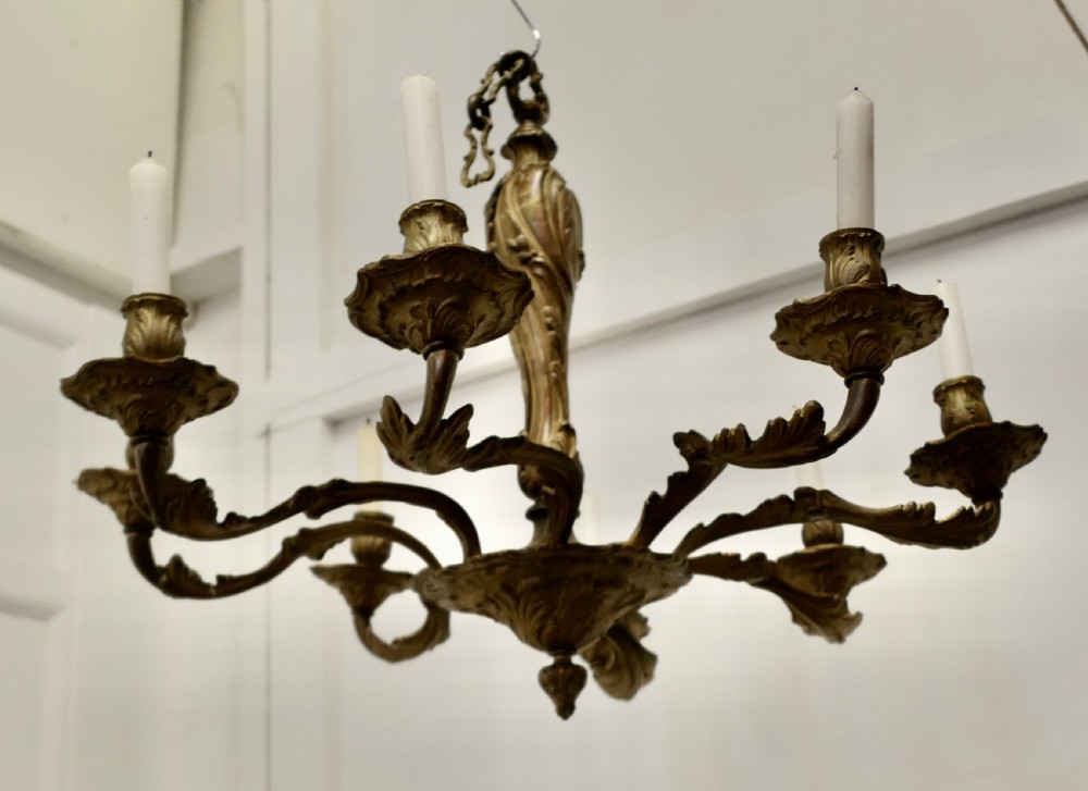An eight-arm French Rococo style chandelier crafted from cast gilded brass with scrolling foliate arms and candle holders. View VI