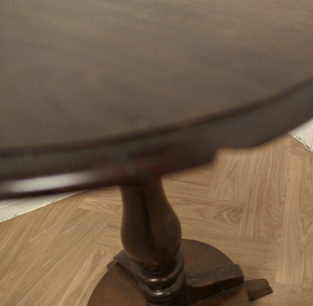 A dark brown wooden Regency style wine table featuring a round top, turned central pedestal, and tripod base. View VI