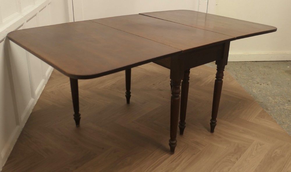 A Victorian mahogany drop-leaf table with turned legs and two hinged rectangular side flaps. View V