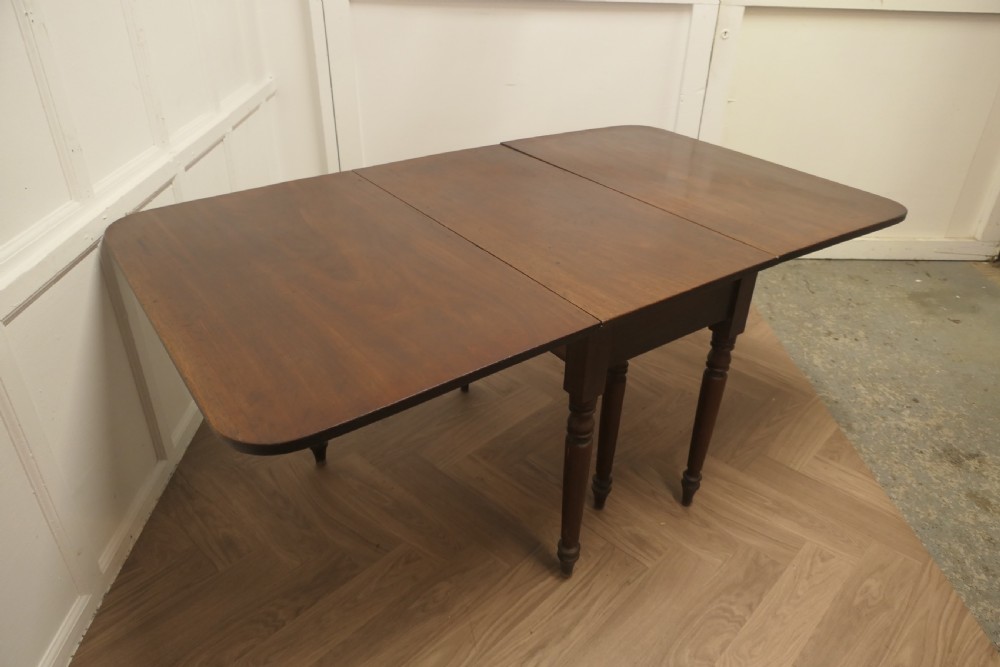 A Victorian mahogany drop-leaf table with turned legs and two hinged rectangular side flaps. View VI
