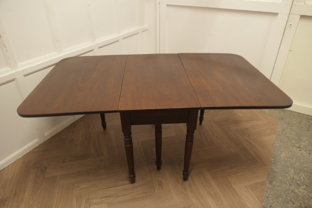 A Victorian mahogany drop-leaf table with turned legs and two hinged rectangular side flaps. View VII