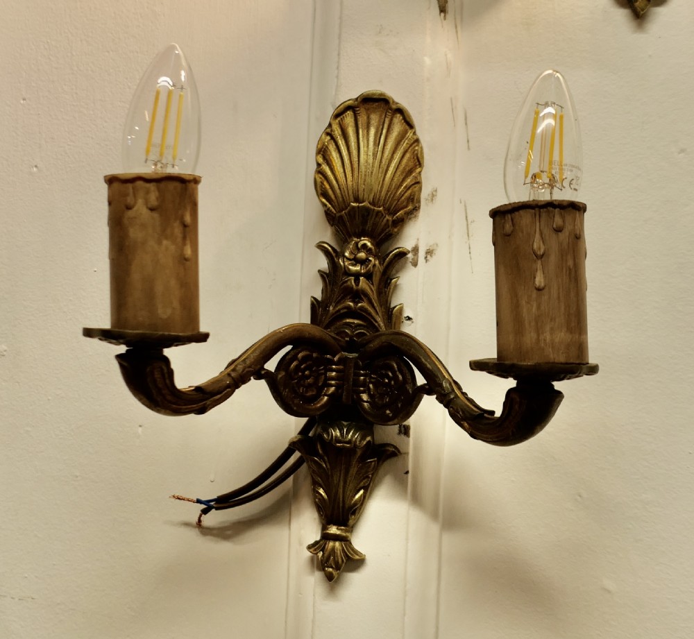 A set of six cast brass twin-branch wall lights featuring scallop shell cresting and twin bulb holders. View IV