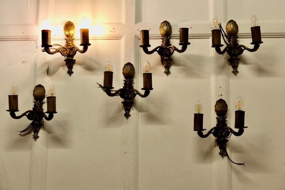 A set of six cast brass twin-branch wall lights featuring scallop shell cresting and twin bulb holders. View VI