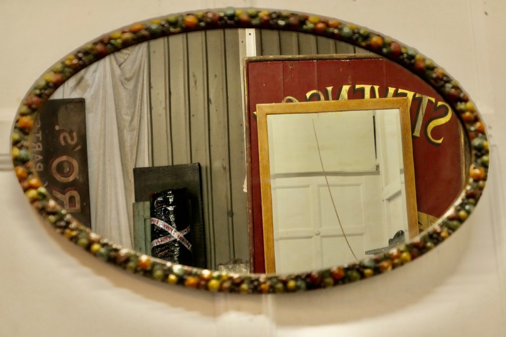 A horizontal oval wall mirror featuring a moulded frame encrusted with detailed polychrome fruit and foliage gesso decorations. View VII