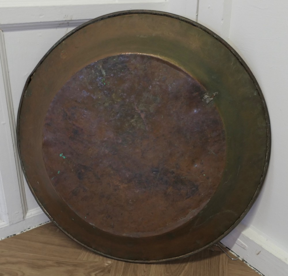 A large round Arts and Crafts hand-hammered copper wall plate displaying a reflective circular central basin and planished rim. View II