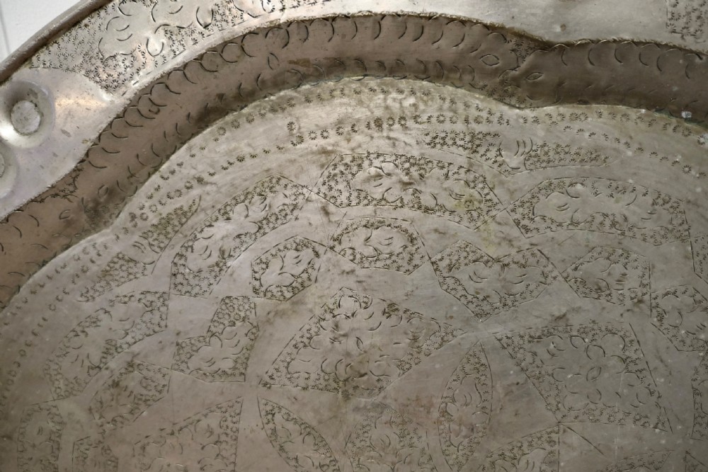 A large circular beaten pewter wall plate featuring intricate hand-hammered geometric engraving with decorative indented rim details. View IV