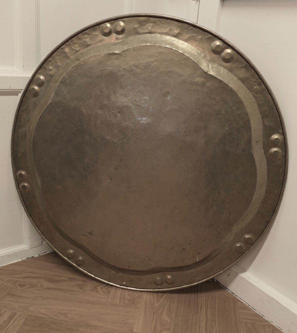 A large circular beaten pewter wall plate featuring intricate hand-hammered geometric engraving with decorative indented rim details. View VI