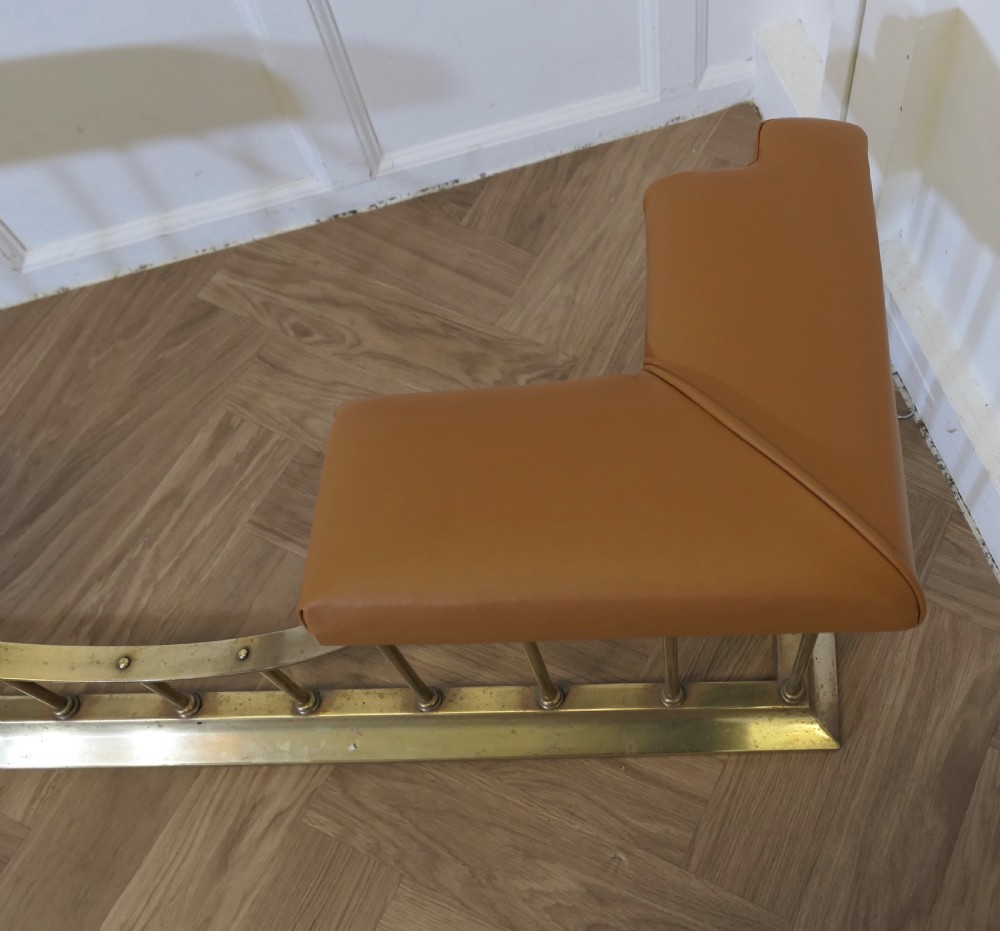 A brass club fender featuring twin tan leather upholstered corner seats supported by vertical brass spindles on a moulded base. View IV