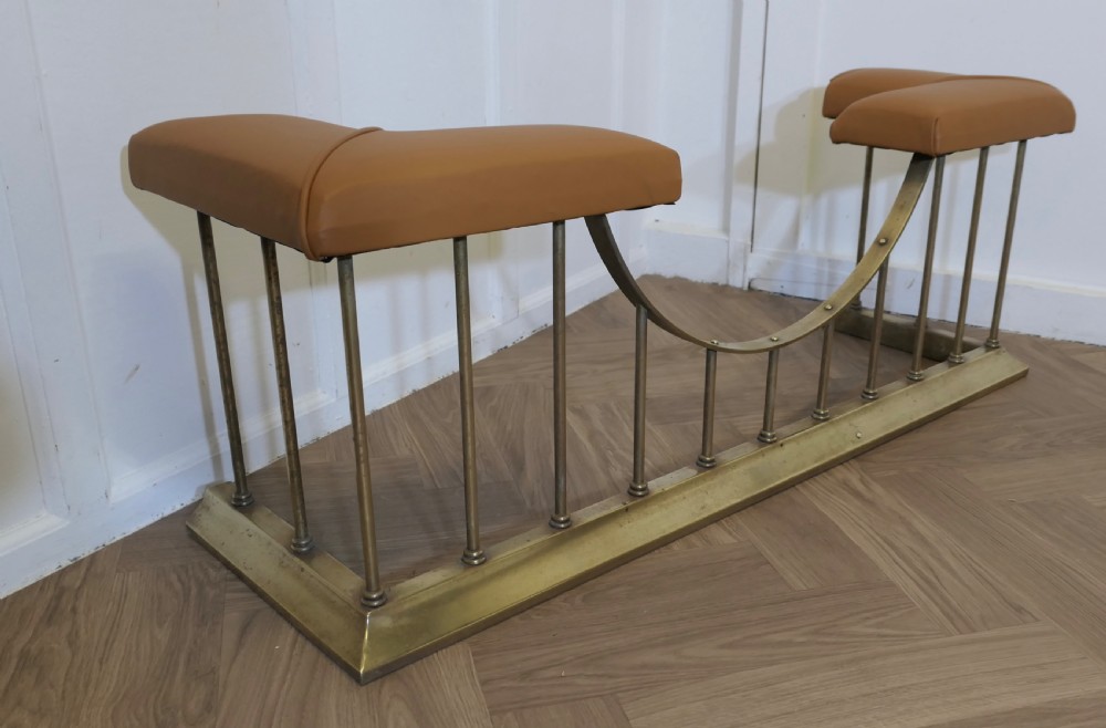 A brass club fender featuring twin tan leather upholstered corner seats supported by vertical brass spindles on a moulded base. View VI
