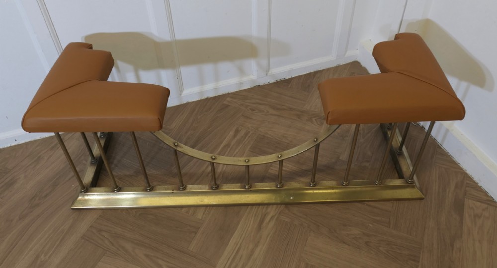 A brass club fender featuring twin tan leather upholstered corner seats supported by vertical brass spindles on a moulded base. View VII
