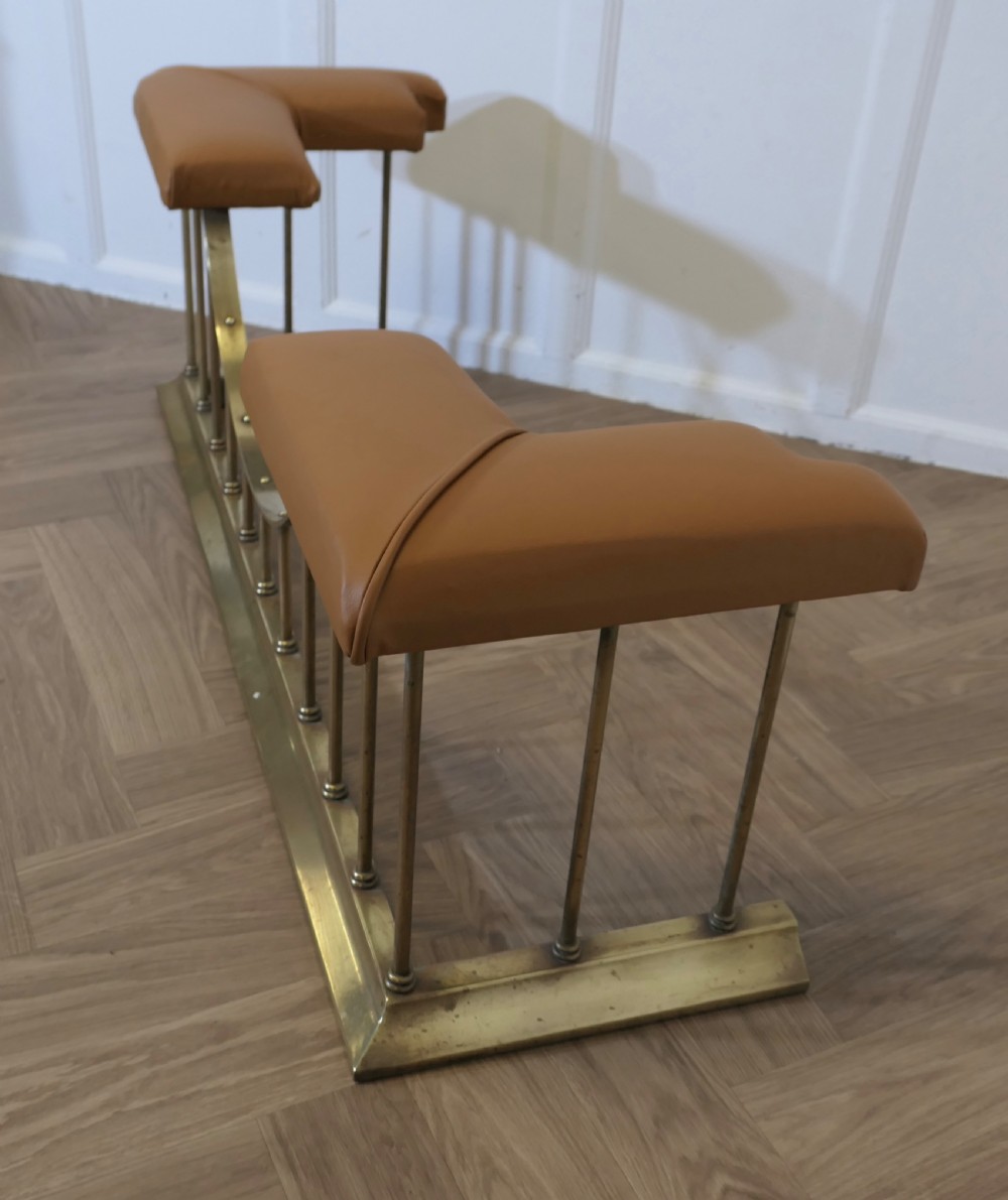 A brass club fender featuring twin tan leather upholstered corner seats supported by vertical brass spindles on a moulded base. View VIII
