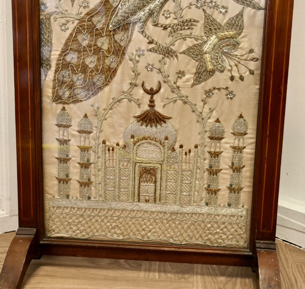 A dark wood framed standing fire screen displaying metallic embroidery of two peacocks and the Taj Mahal. View VI