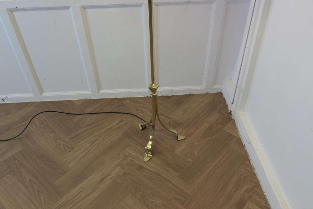 An Arts and Crafts brass standard floor lamp featuring a tapered column, splayed tripod feet, and a flared light pink shade. View VI