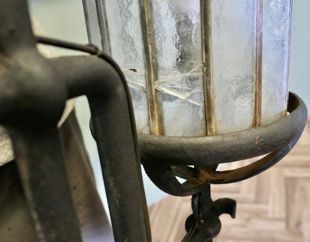 A pair of large black wrought iron wall lanterns featuring cylindrical glass shades with vertical metal bars and decorative finials at the top and bottom. View V