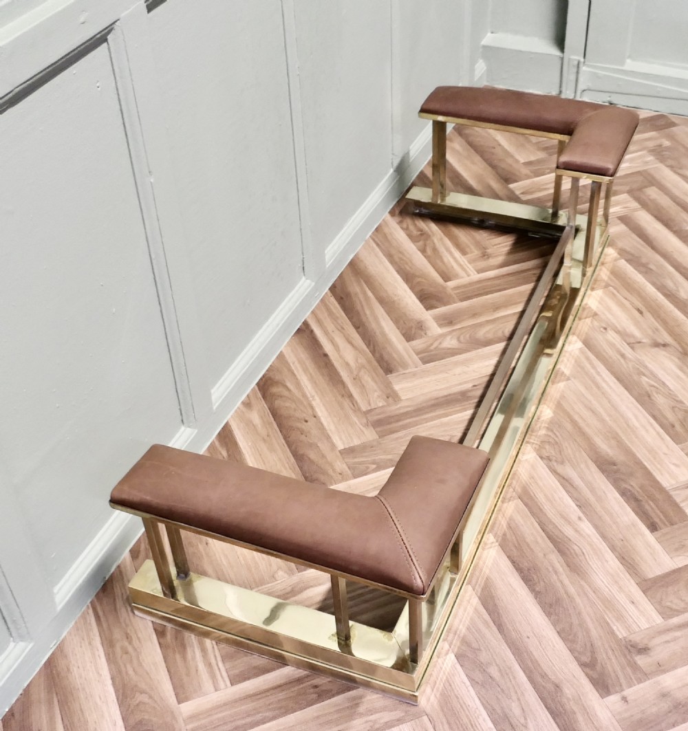 An Art Deco polished brass club fender featuring two corner seats upholstered in tan leather. View III