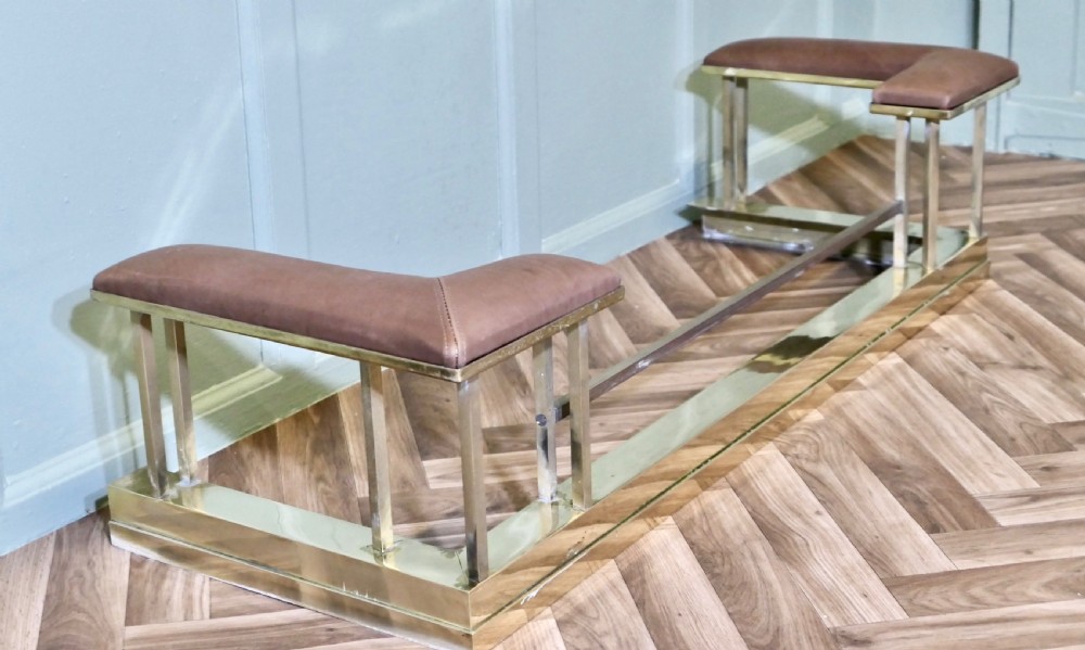 An Art Deco polished brass club fender featuring two corner seats upholstered in tan leather. View V