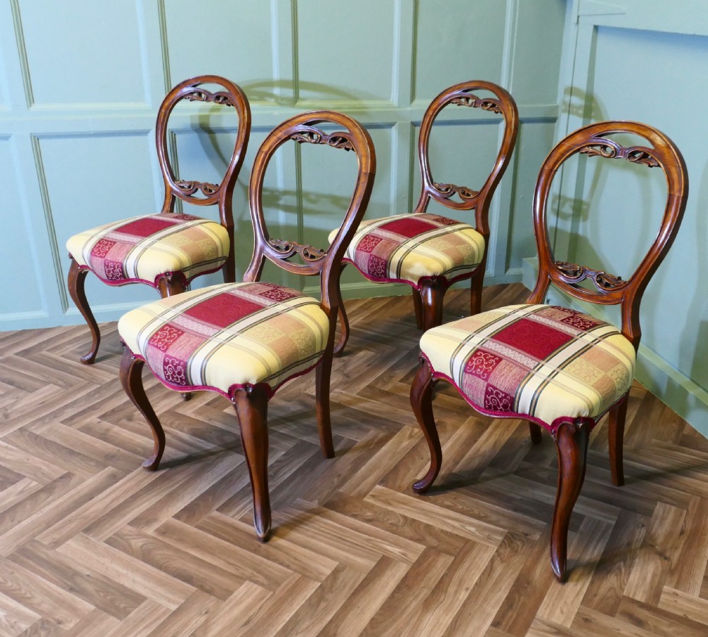 A set of four Victorian mahogany dining chairs featuring carved balloon-shaped backframes, cabriole front legs, and patterned upholstered seats. View II