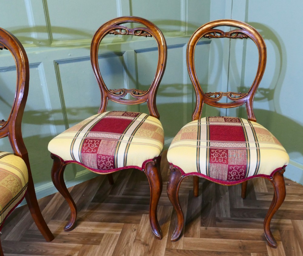 A set of four Victorian mahogany dining chairs featuring carved balloon-shaped backframes, cabriole front legs, and patterned upholstered seats. View III