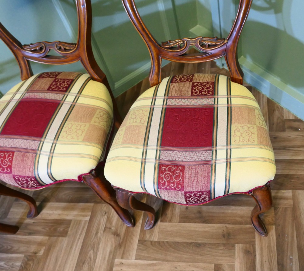 A set of four Victorian mahogany dining chairs featuring carved balloon-shaped backframes, cabriole front legs, and patterned upholstered seats. View IV